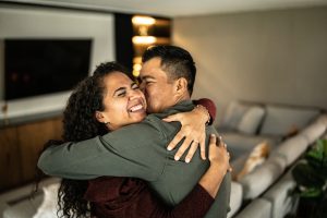 An adult couple embracing in the living room at home